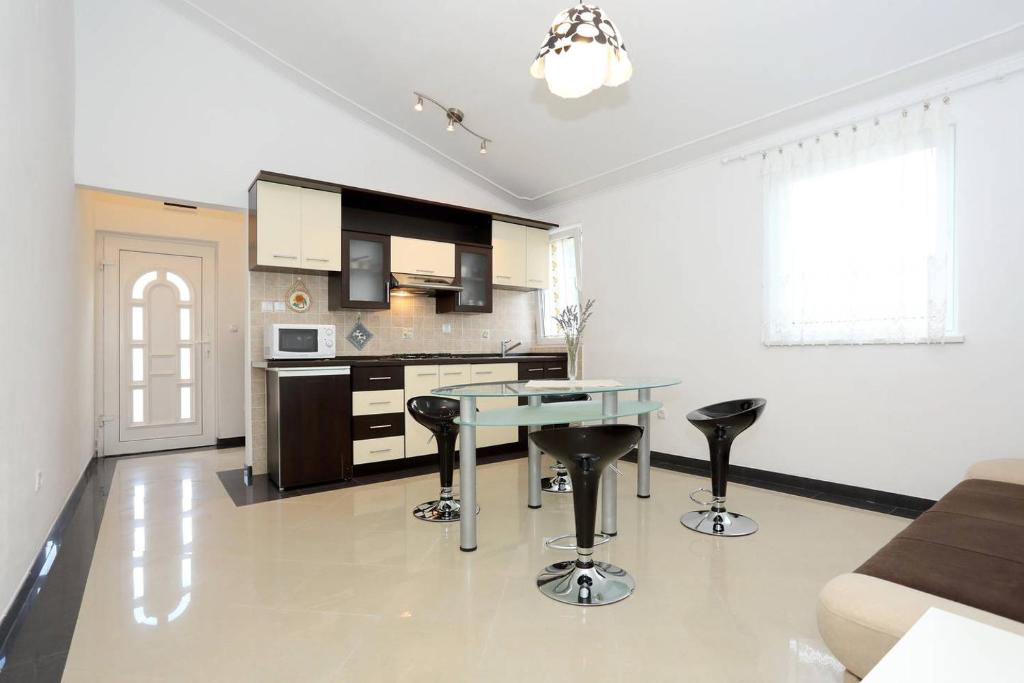 a kitchen with a glass table and black stools at Apartmani Mlinar in Gornji Karin