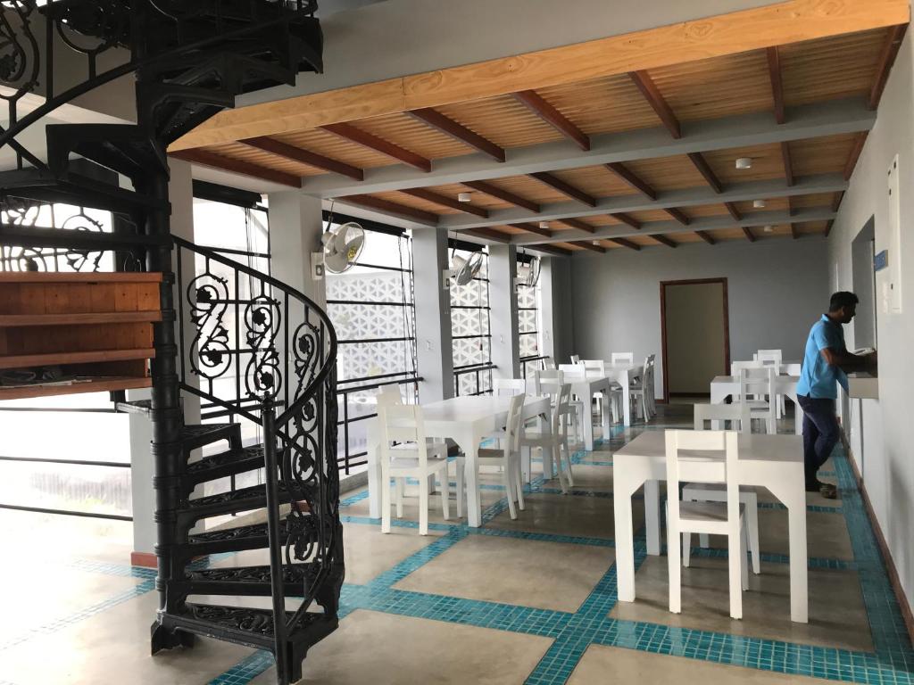 a man standing in a room with white tables and chairs at Araliya OceanFront Condos Nilaveli, Trincomalee in Nilaveli