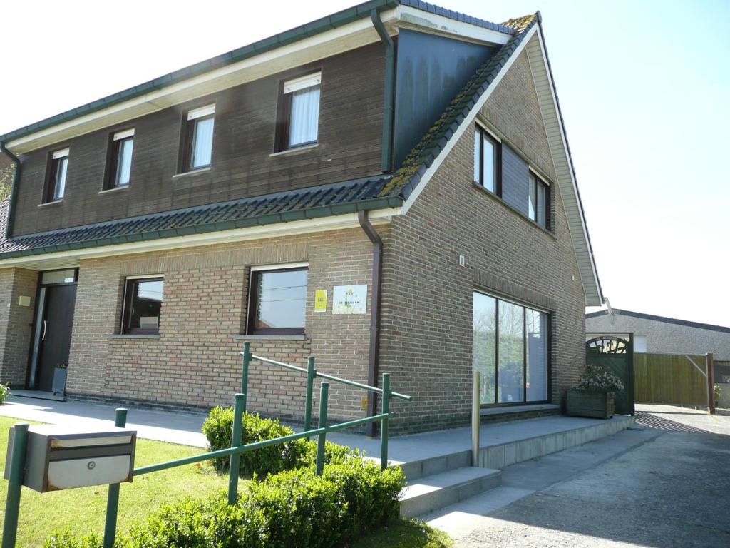 un edificio de ladrillo con una escalera delante de él en De Windroos, en Pollinkhove