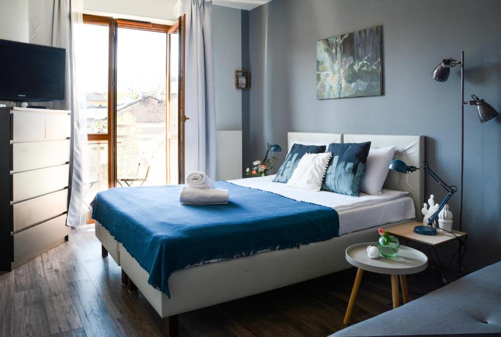 um quarto com uma cama com lençóis azuis e uma televisão em Vinyl Apartment Old Town em Cracóvia