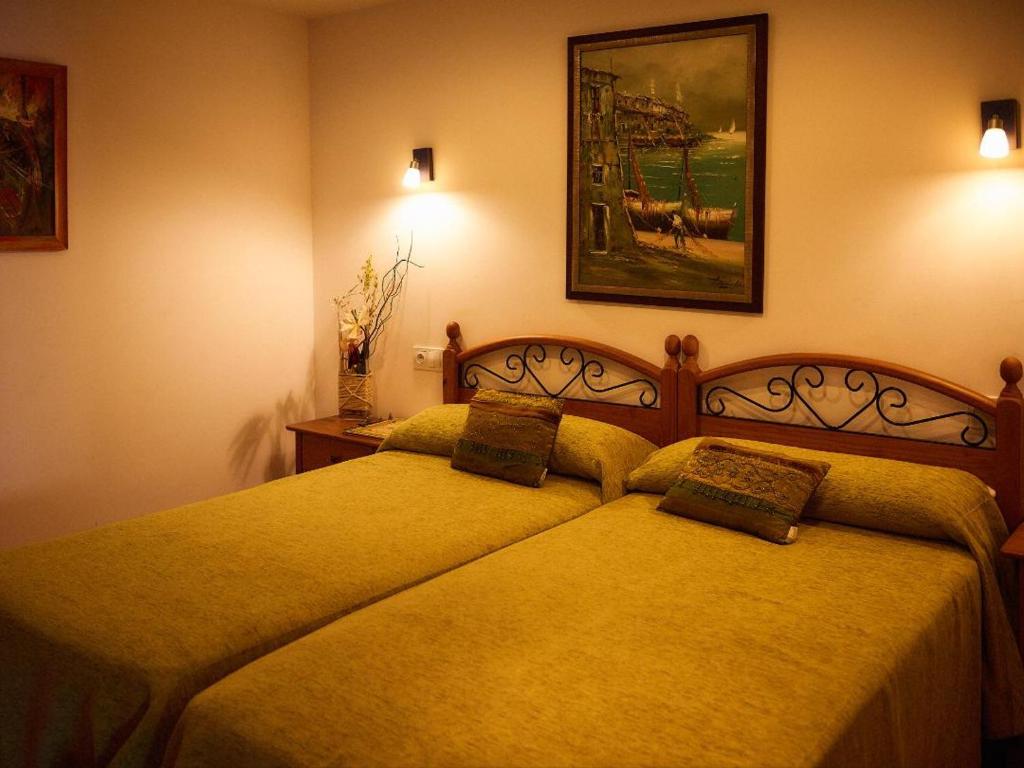two beds in a hotel room with yellow sheets at As Chivas in Redondela
