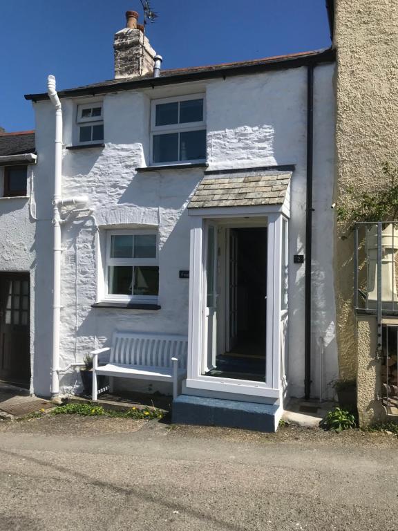 a white house with a bench in front of it at Froglets in Tregoney