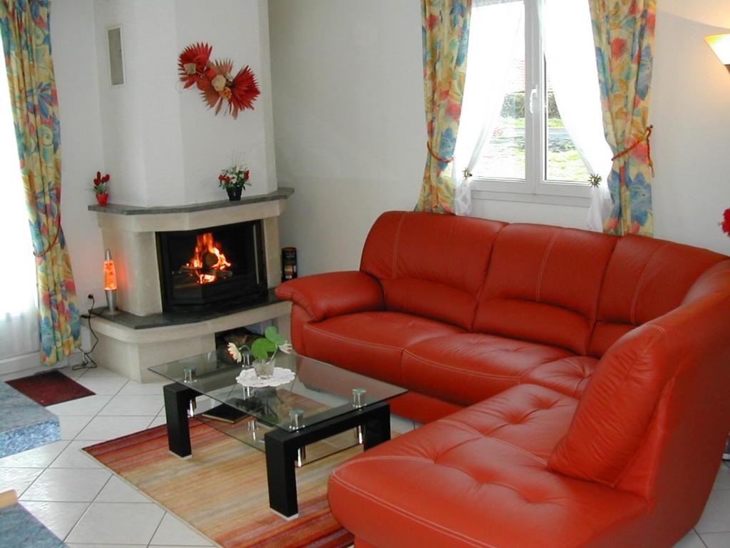 salon z czerwoną kanapą i kominkiem w obiekcie Gîte Dieppe w mieście Auppegard