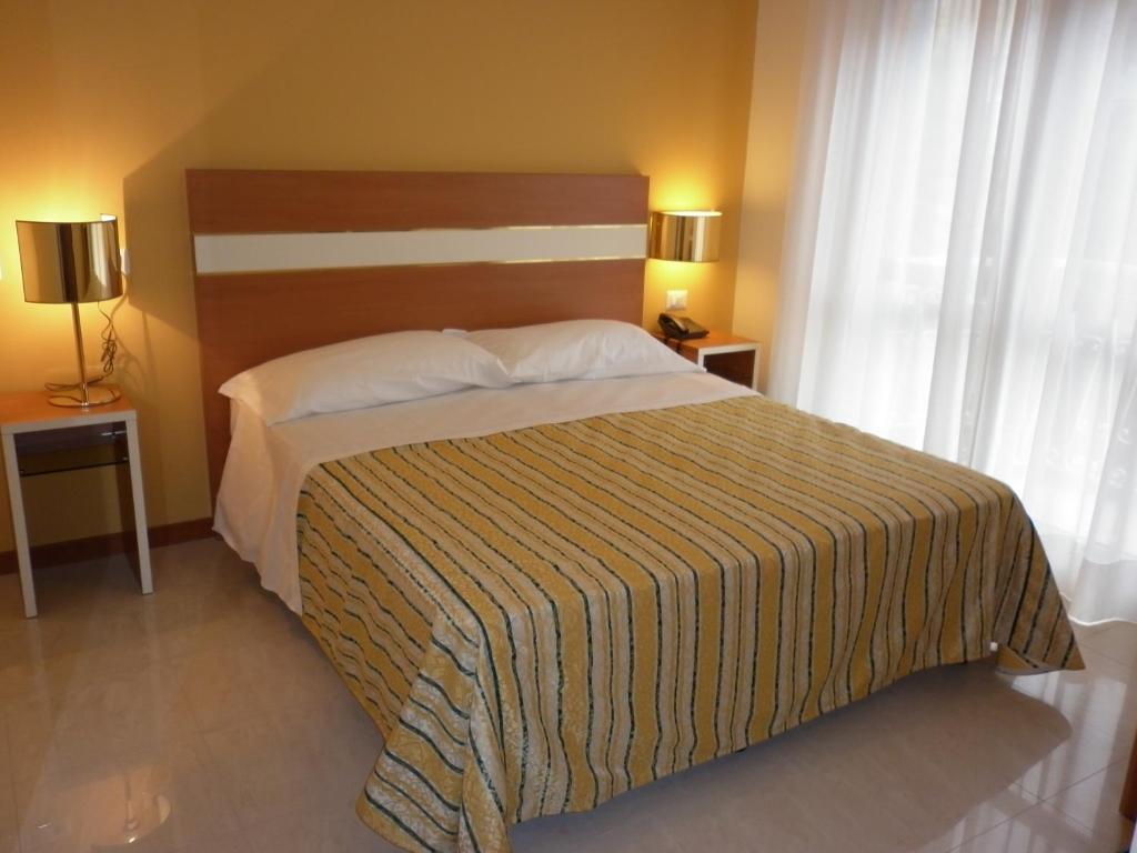 1 dormitorio con 1 cama con colcha a rayas en Hotel GF, en Cesano Boscone
