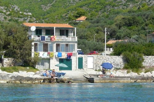 una casa en la playa con gente sentada bajo sombrillas en Apartments Gabrijela, en Prizba