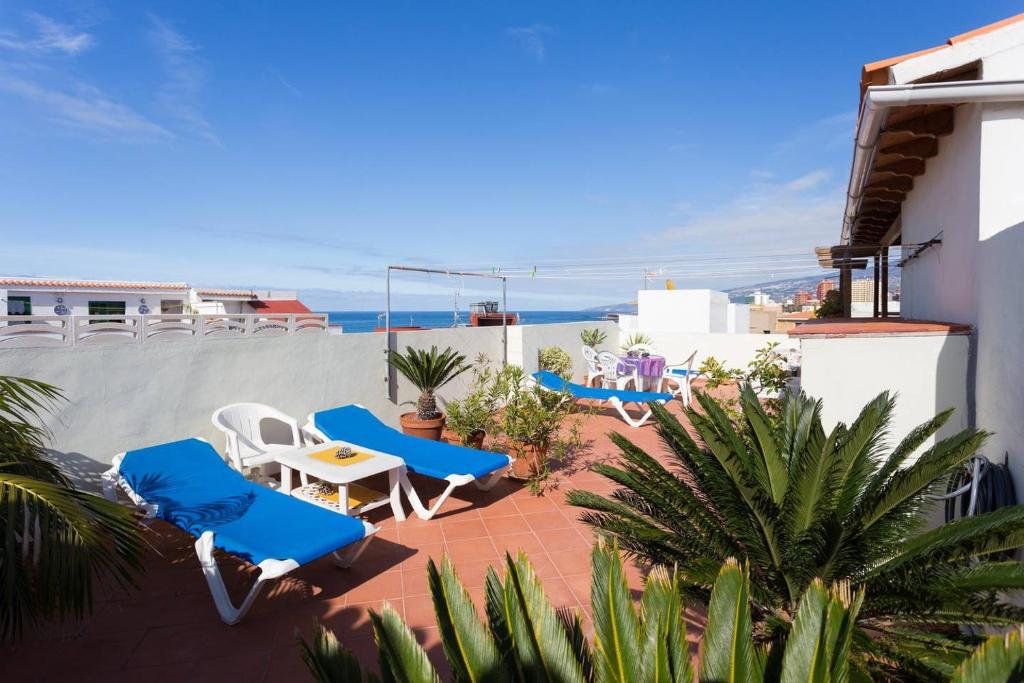 a patio with blue and white chairs and the ocean at Apartamento 3 en Casa Rosamar in Puerto de la Cruz