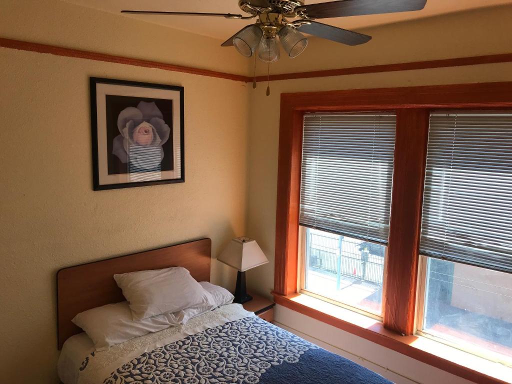 a bedroom with a bed with a fan and two windows at Boston Hotel in San Francisco