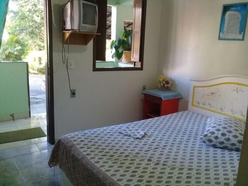 1 dormitorio con cama, espejo y TV en BZ Suites, en Búzios
