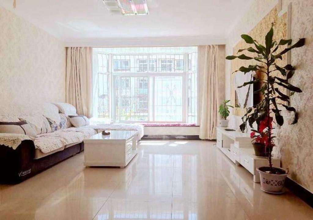 a living room with a couch and a large window at Beidaihe Haizhilian Holiday Apartment in Qinhuangdao
