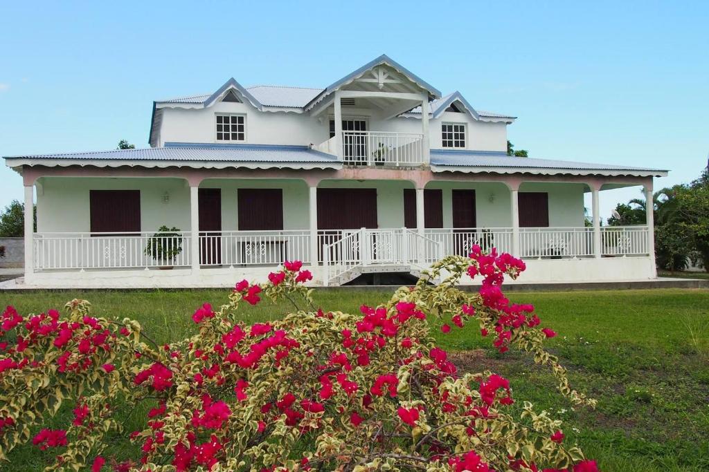 una casa blanca con flores rojas en primer plano en Haut de villa, en Sainte-Rose