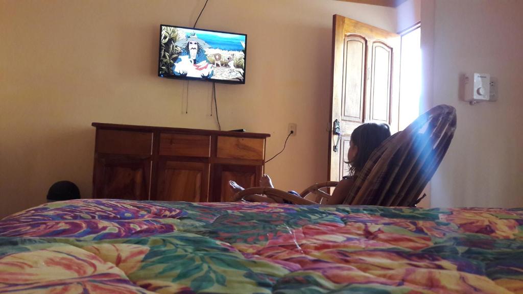 a person sitting in a chair watching a television at Cabinas Doña Alicia in Quepos