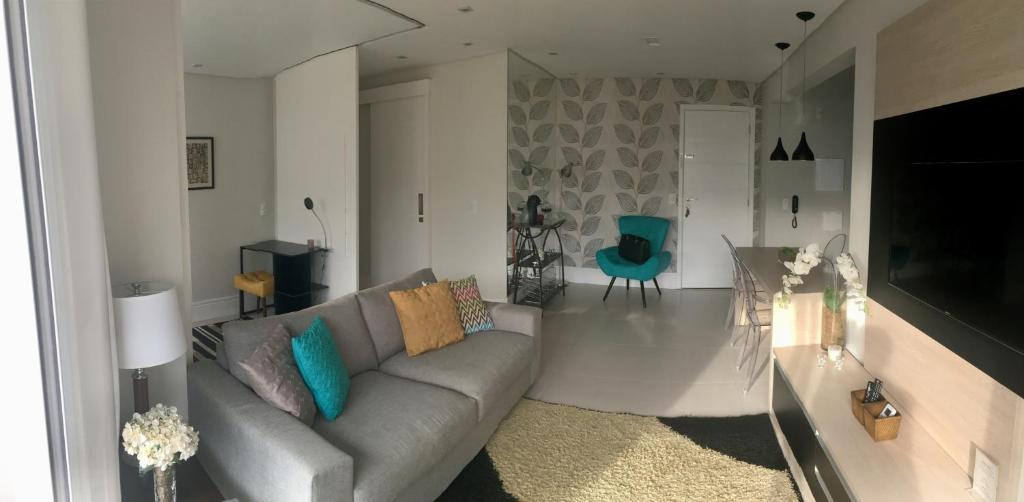 sala de estar con sofá gris y silla azul en Apartamento Menara Morumbi, en São Paulo