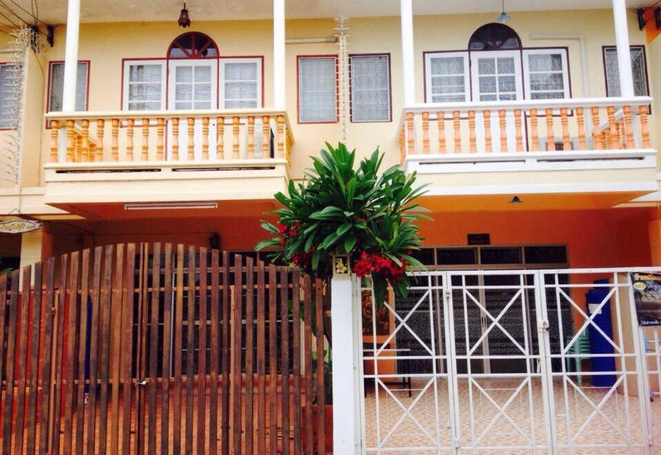 a house with a fence and a palm tree in front of it at Baan Khun Nong in Phetchaburi