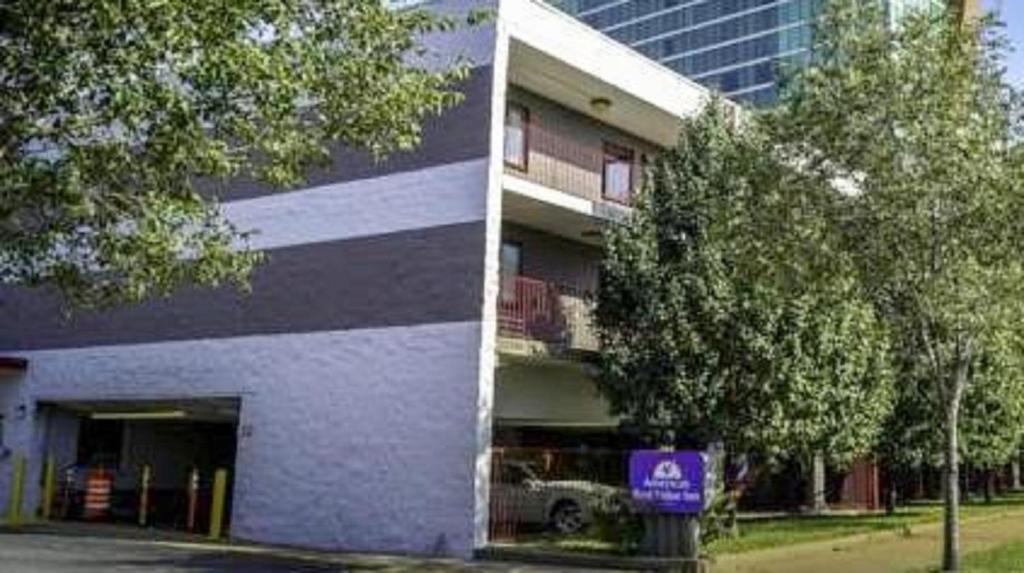 Americas Best Value Inn St. Louis Downtown في سانت لويس: مبنى فيه لافته للمواقف بجانب شجره