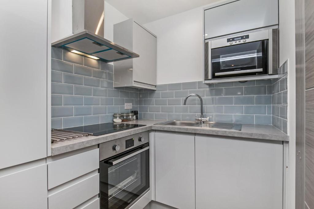 uma cozinha com armários brancos, uma pia e um micro-ondas em Paddock Drive em Winchester