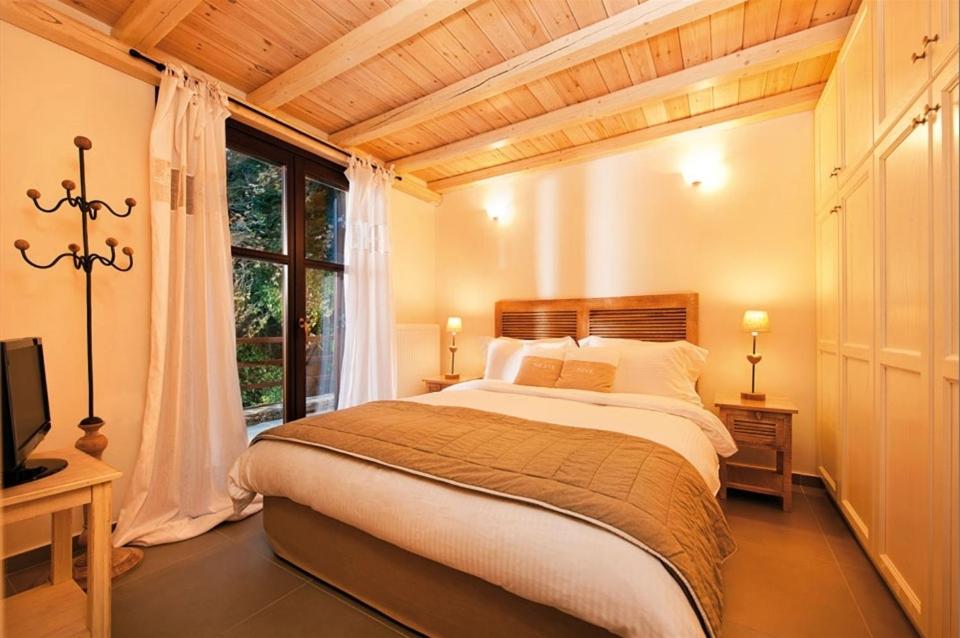 a bedroom with a large bed and a window at Vergopoulos Oliveyard in Mouresi