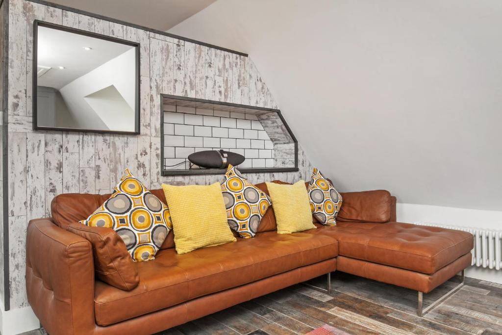 a brown leather couch with yellow pillows in a living room at Paddock View in Winchester