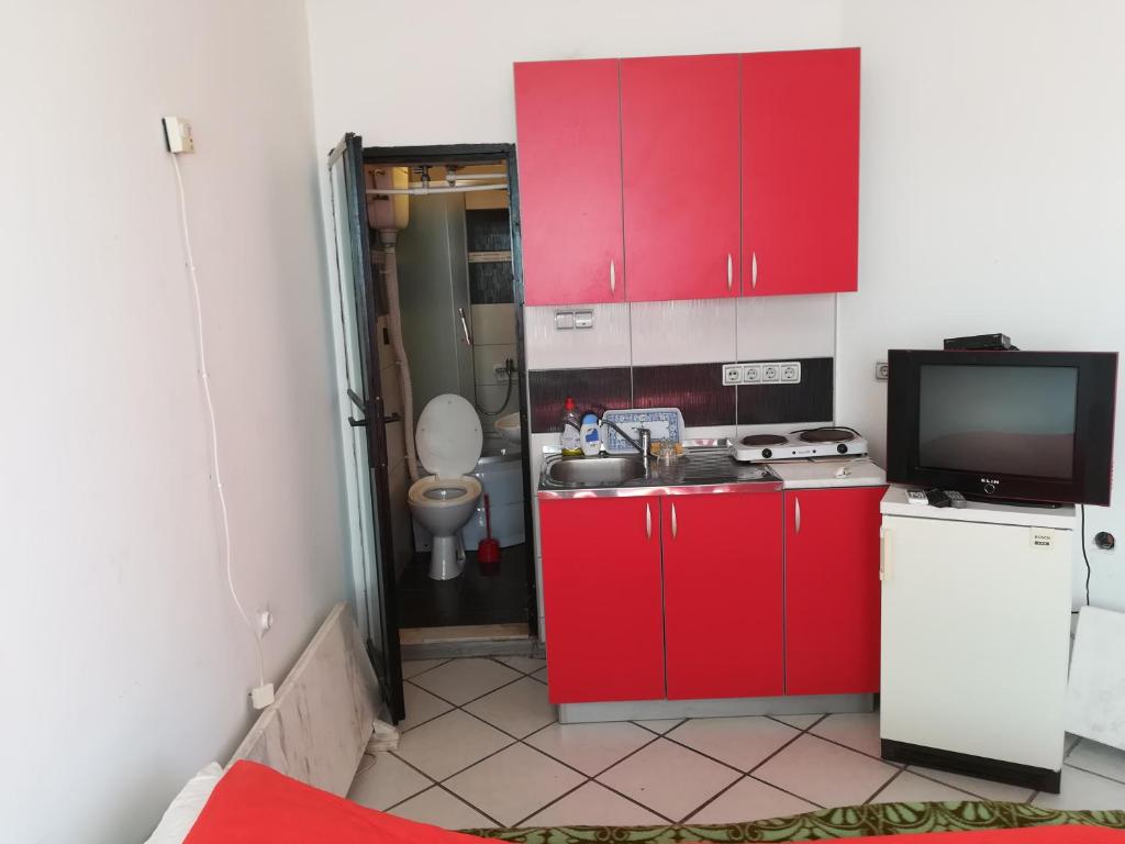 cocina pequeña con armarios rojos y TV en Apartmani Filipovic, en Kladovo