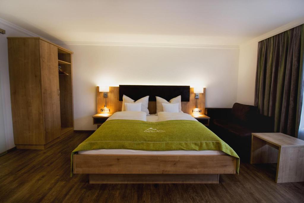 a bedroom with a large bed with a green blanket at Hotel Alp Inn in Ruhpolding