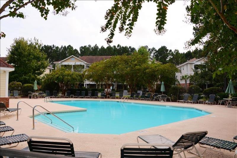 a large blue swimming pool with chairs and tables at 613 River Crossing Condo in North Myrtle Beach