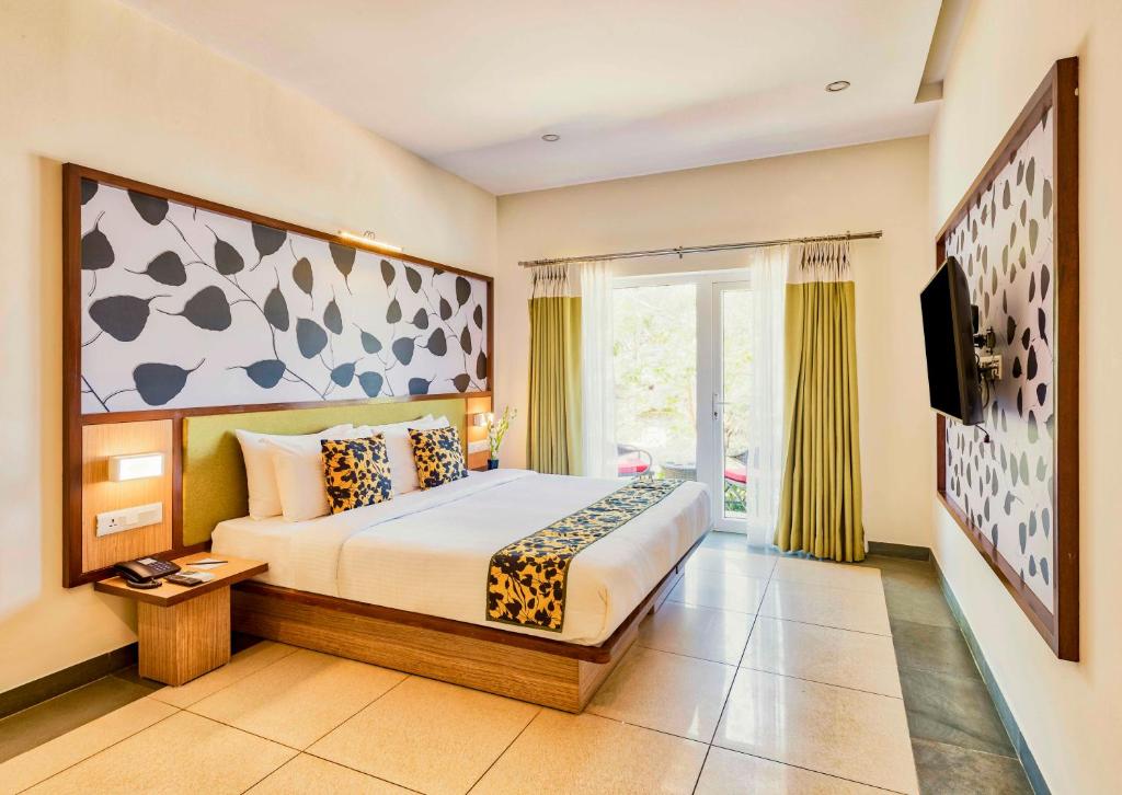 a bedroom with a bed and a large window at Sterling Wayanad in Sultan Bathery