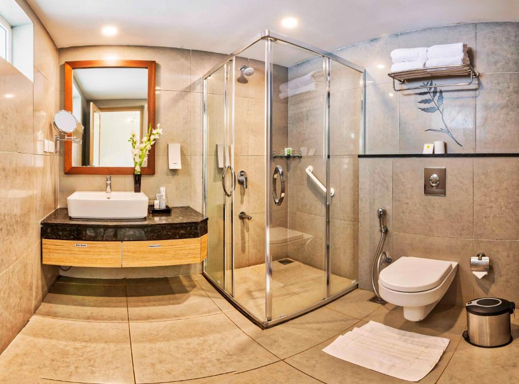 a bathroom with a shower and a sink and a toilet at Sterling Wayanad in Sultan Bathery