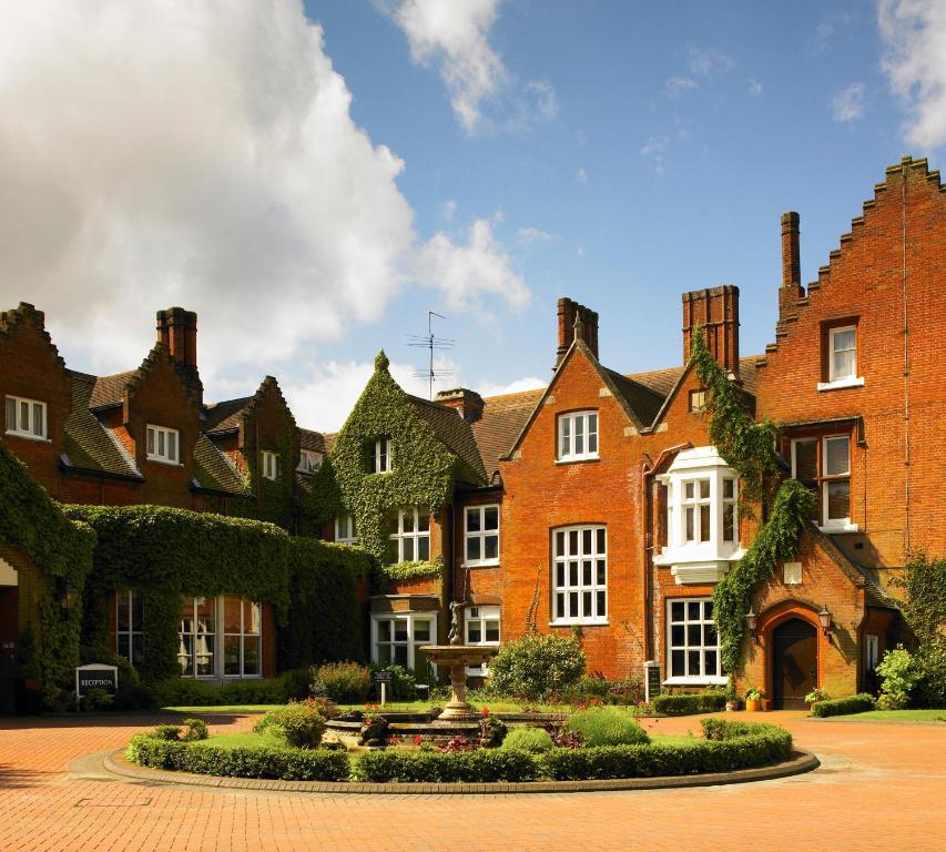 a large brick building with a clock on the front of it at Sprowston Manor Hotel, Golf & Country Club in Norwich