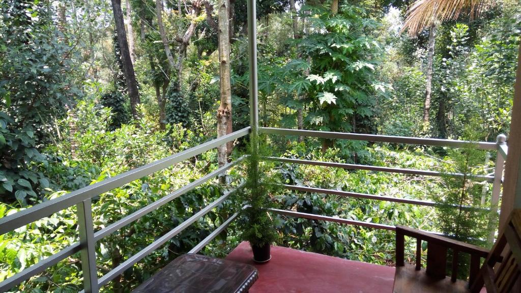 a balcony with a view of a forest at StaySimple Spicefarm in Somvārpet