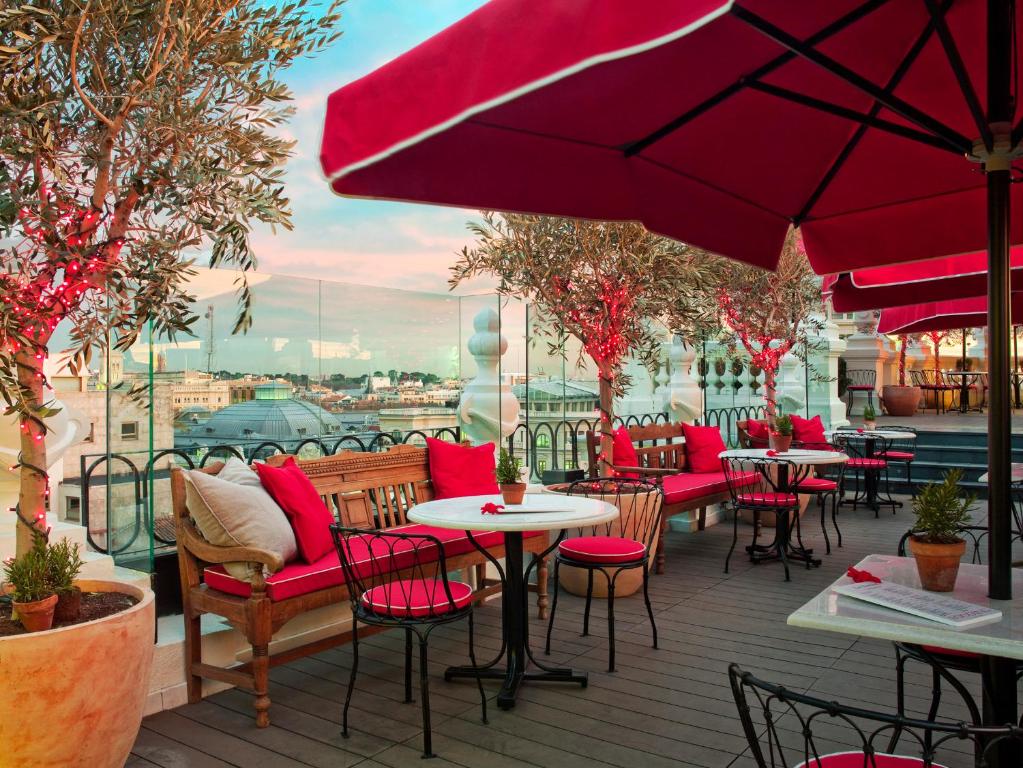 a patio with tables and chairs and red umbrellas at The Principal Madrid, Small Luxury Hotels in Madrid