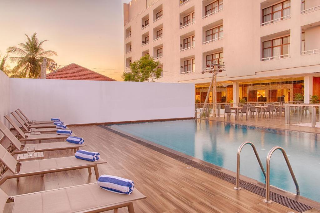 a pool at a hotel with lounge chairs at NorthGate Jaffna in Jaffna