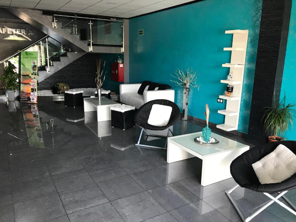 a lobby with chairs and tables and a blue wall at Hostal Kavanna in San Pedro de Mérida