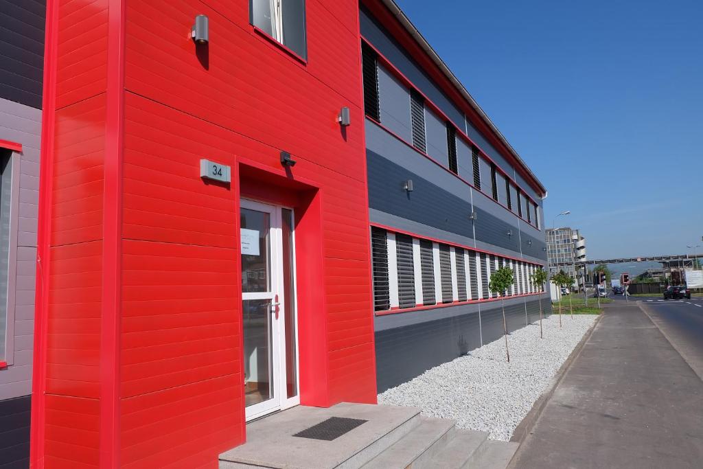 ein rotes Gebäude mit einer roten Wand an einer Straße in der Unterkunft Montagehotel Bed & Steel in Linz