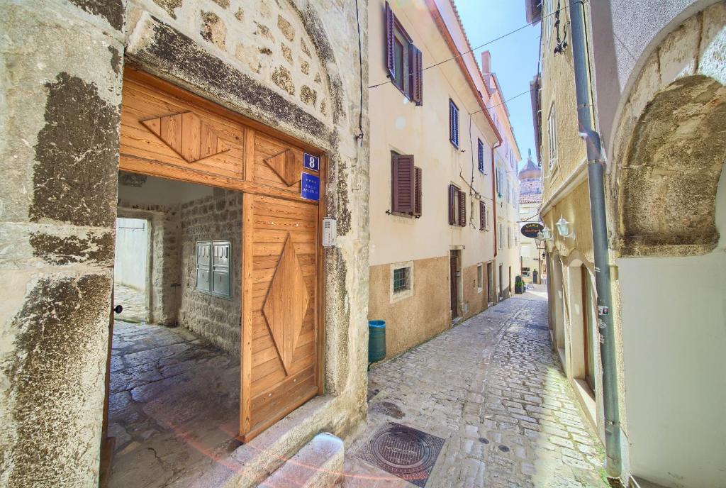 an alley with a wooden door on a building at Hrast in Krk