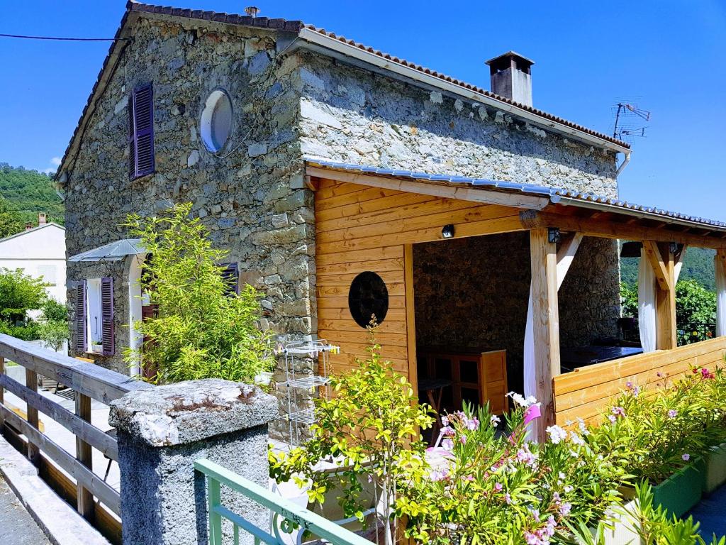 a small stone house with a fence and flowers at Gîte casa di l'Apa in Venaco