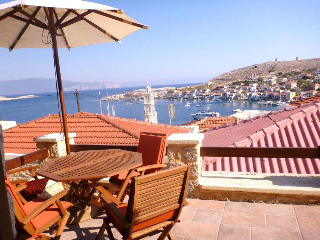 einen Tisch und Stühle auf einem Balkon mit Sonnenschirm in der Unterkunft Bright Sun Villas in Chalki