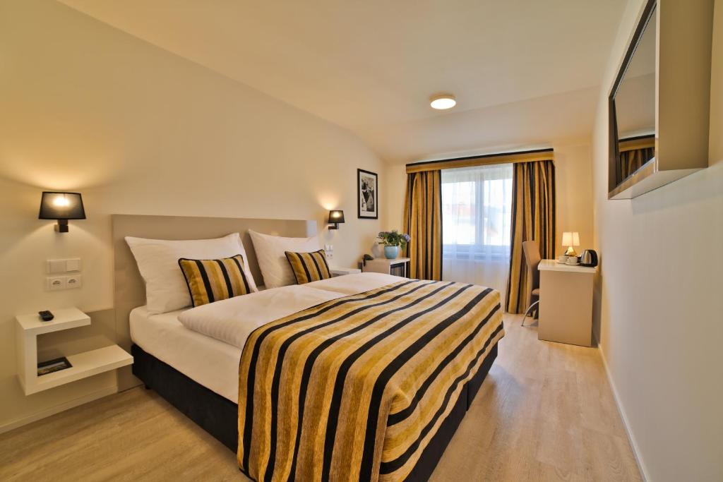 - une chambre avec un grand lit et une couverture rayée dans l'établissement Hotel Ariston Prague, à Prague