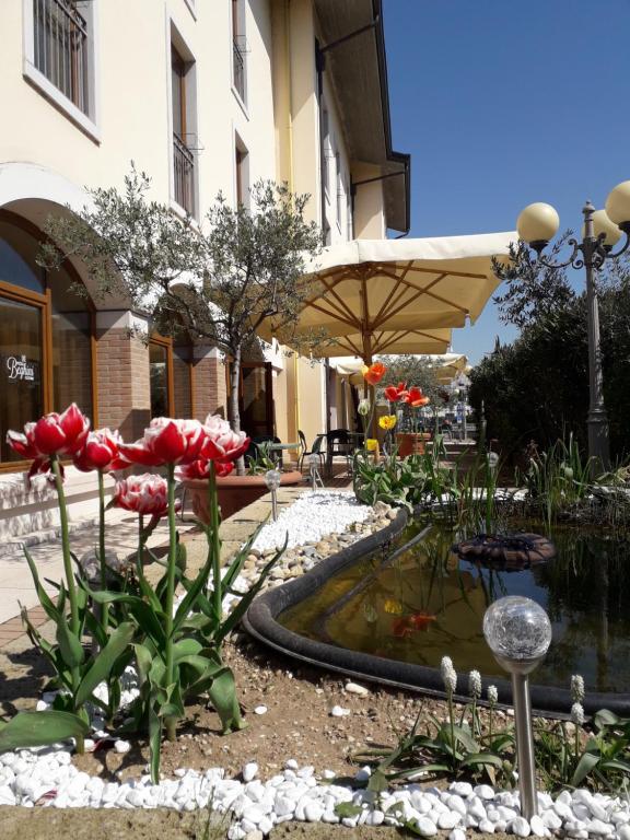 un jardin avec des tulipes rouges et un étang en face d'un bâtiment dans l'établissement Hotel Scaligero, à Sommacampagna