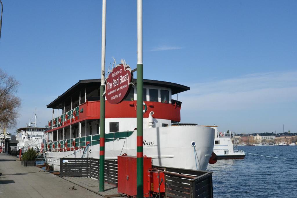 a boat docked next to a building on the water at Den Röda Båten in Stockholm