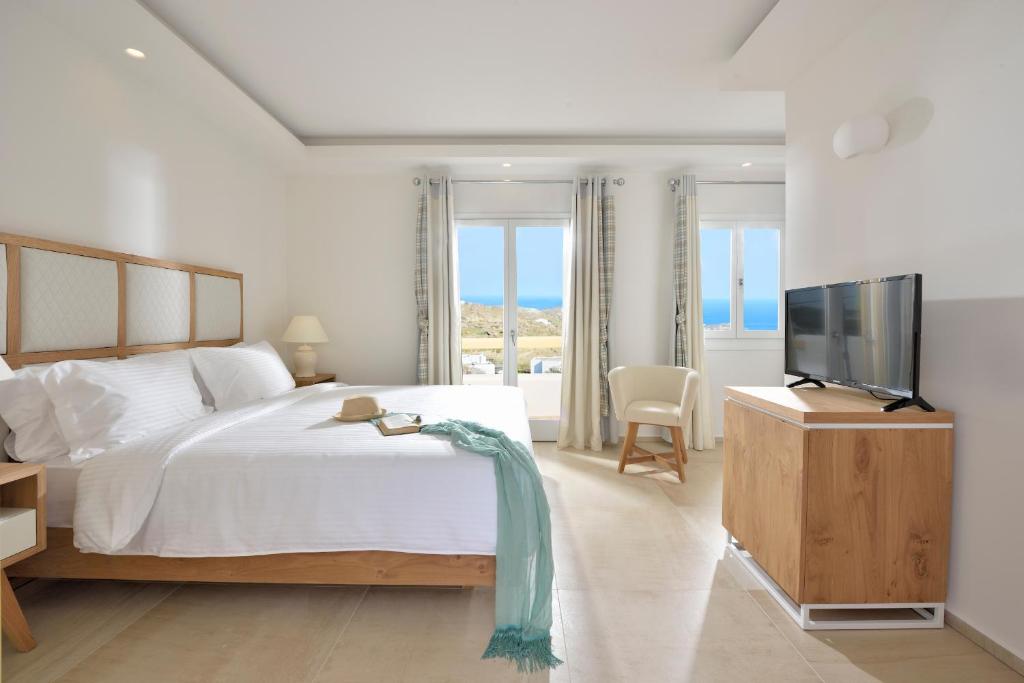 a white bedroom with a bed and a television at Jenny's Summer Houses in Platis Gialos