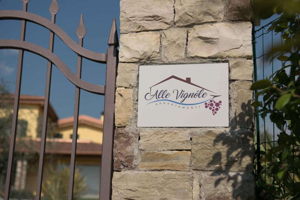 ein Schild an einer Steinmauer neben einem Tor in der Unterkunft Alle Vignole in Garda