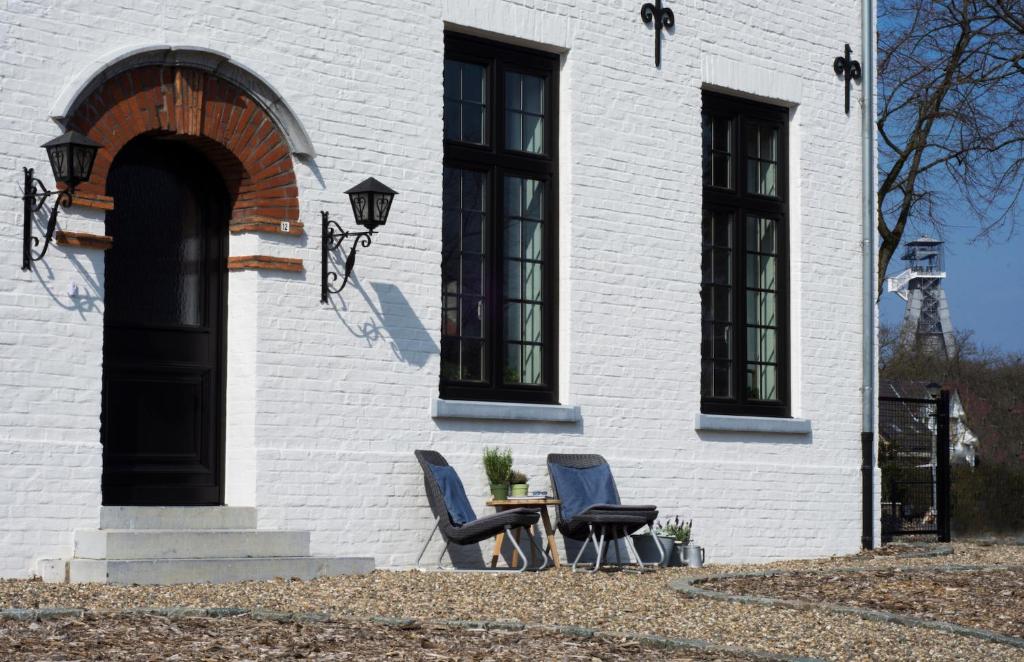 2 chaises et une table en face d'un bâtiment dans l'établissement B&B Eikenlaan 12, à Genk