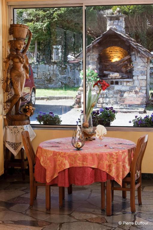 a table with a red table cloth and a stone fireplace at Hôtel Le Catala in Beaudéan