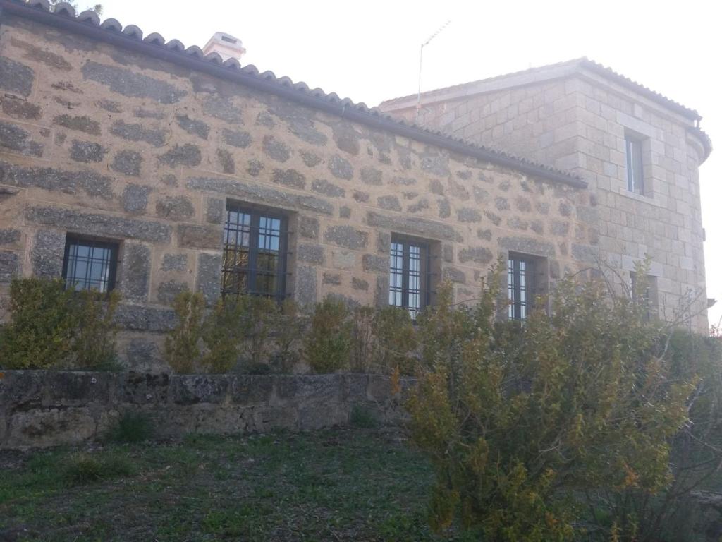 an old stone building with windows on the side of it at Casa Rural de Benjamin Palencia in Villafranca de la Sierra