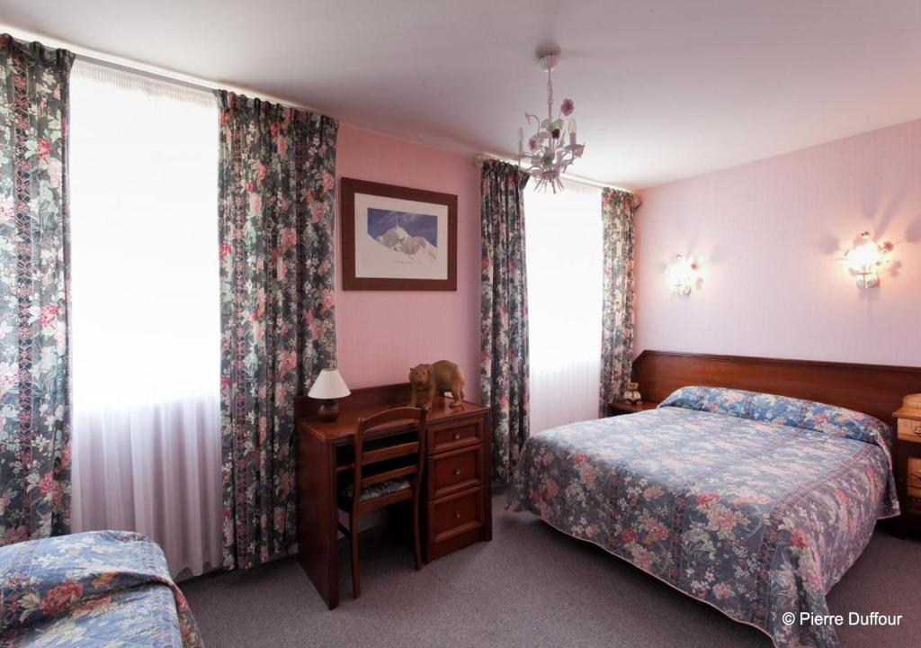 a bedroom with two beds and a desk and curtains at Hôtel Le Catala in Beaudéan