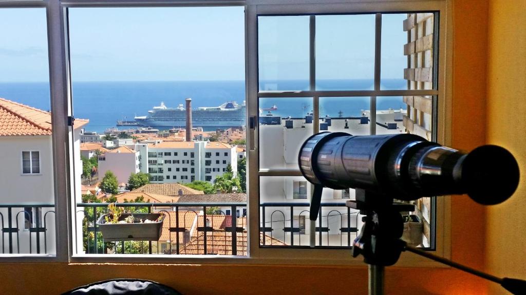 a camera in a window with a view of a city at Top Floor With Balcony in Funchal in Funchal