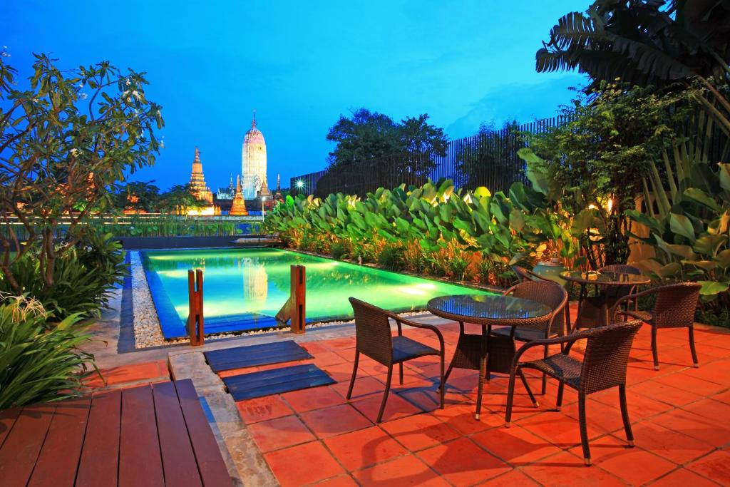 un patio con mesas y sillas junto a una piscina en iuDia Hotel, en Phra Nakhon Si Ayutthaya
