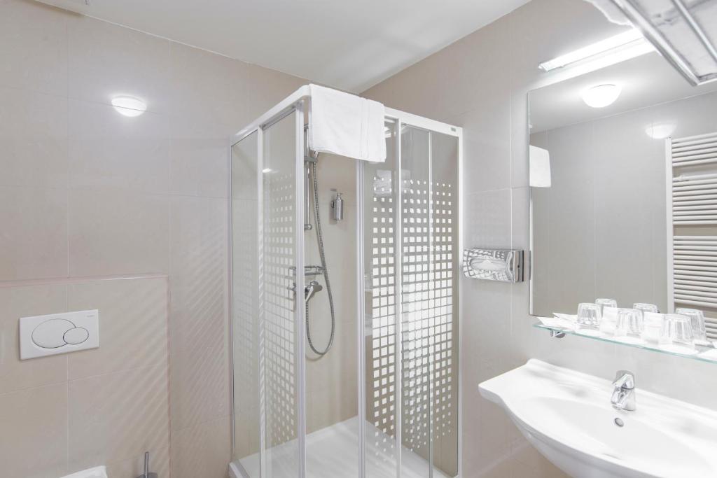 a white bathroom with a shower and a sink at Hotel Páv in Prague