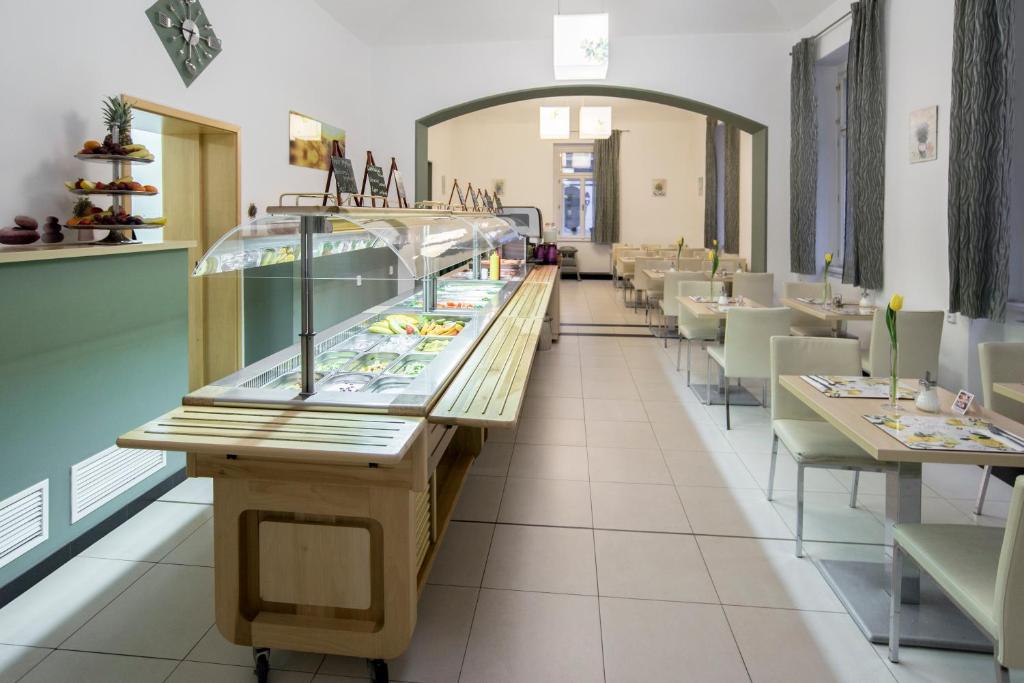 a restaurant with a glass counter and tables and chairs at Hotel Páv in Prague