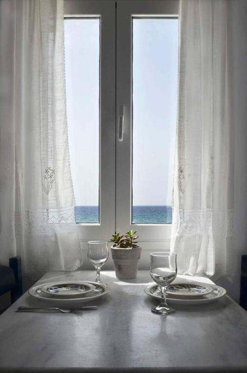 a table with two plates and wine glasses on it at Almira Studios in Kionia