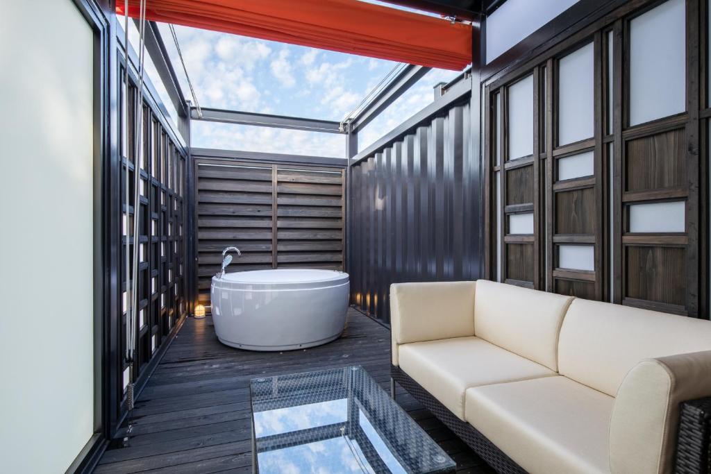 a living room with a tub and a couch at HOTEL R9 Kujukuri "ex Casual Resort COFF Ichinomiya" in Ichinomiya